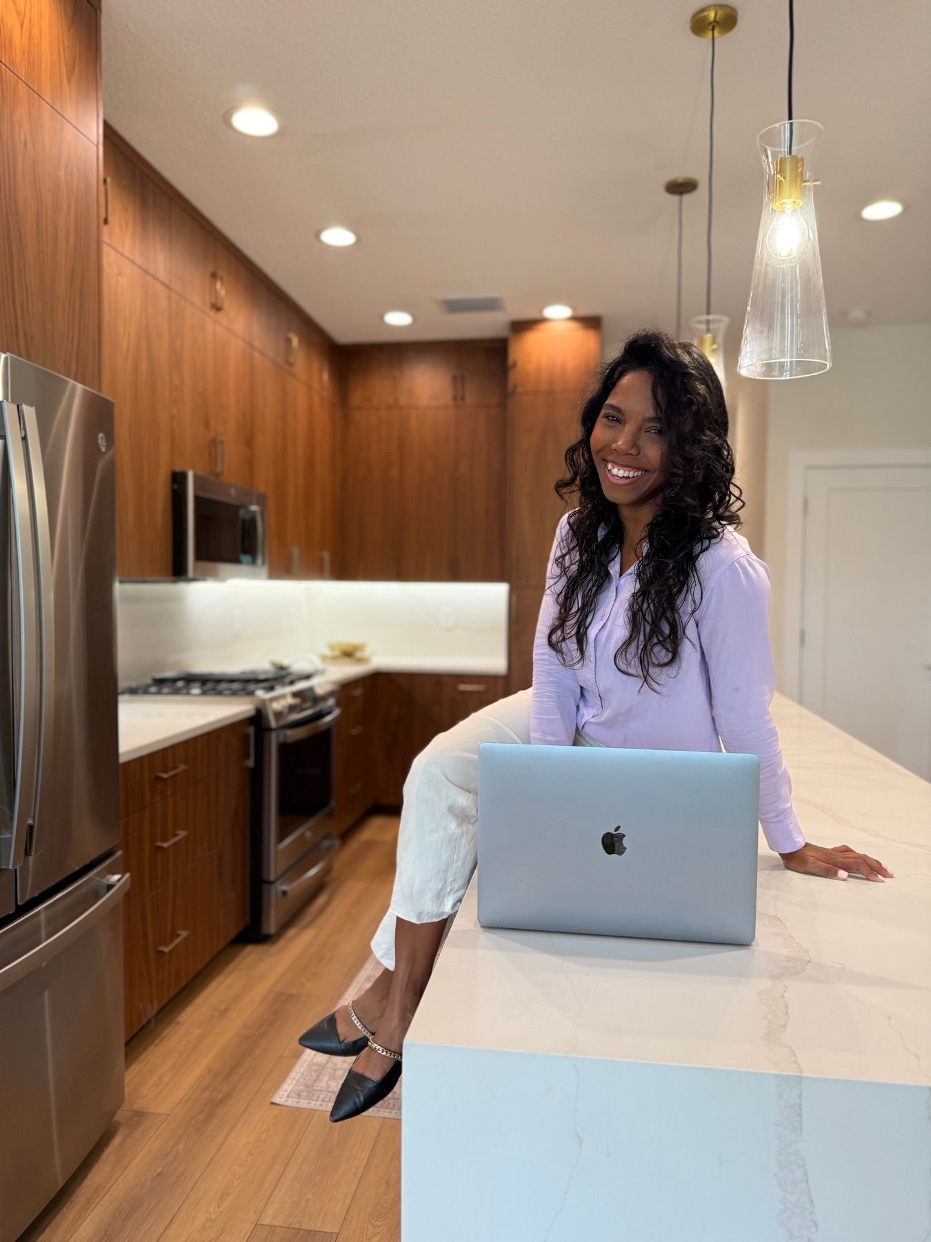 Maria sitting on a kitchen counter next to her laptop, smiling