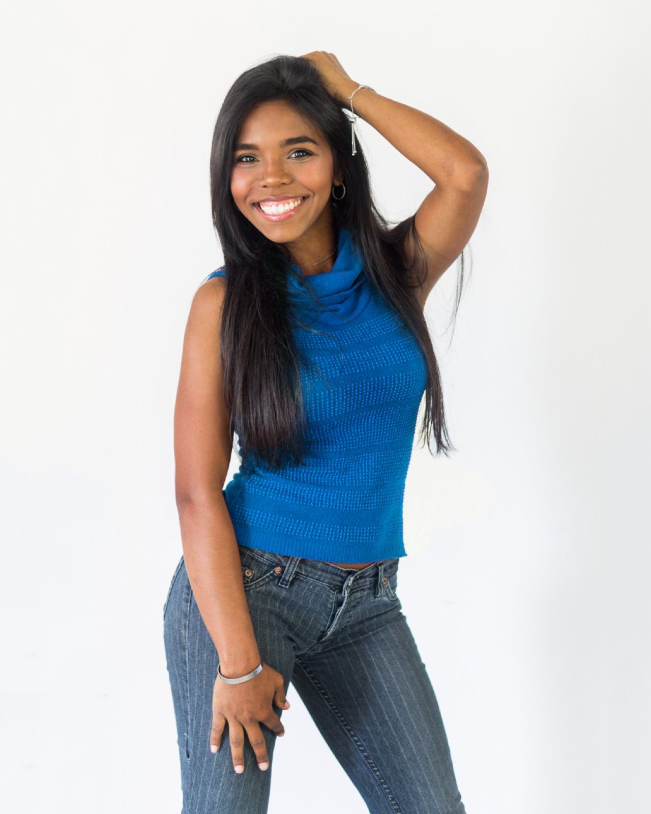 Maria Happy smiling, in a blue top against a white wall